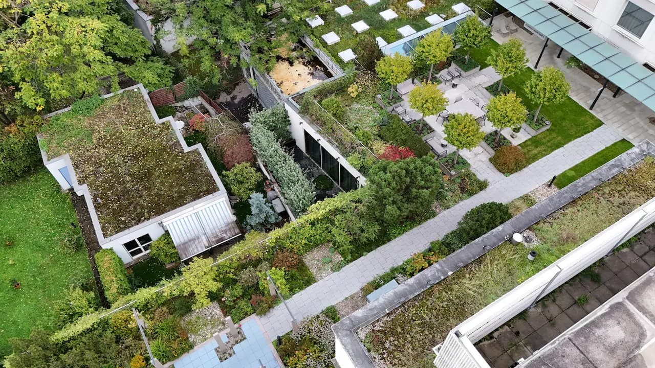 Jardins urbains et toits verts pour la biodiversité dans les Oases 3Bee Vue aérienne d'un jardin urbain avec des toits verts et des chemins piétonniers, faisant partie d'une Oasis 3Bee